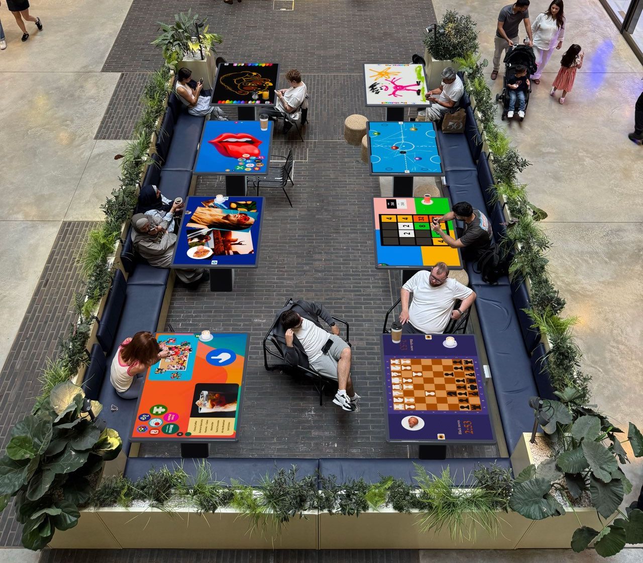 Guests playing games on smart tables in a busy shopping centre café